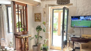 Un salón acogedor con un sofá de cuero marrón, una mesa de centro de madera y un televisor mostrando un partido deportivo.