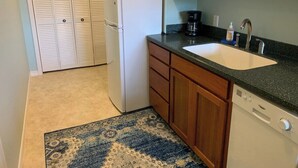 A compact kitchen with a refrigerator, sink, and dishwasher.