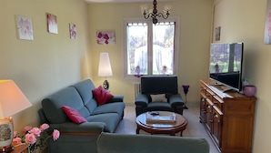 A living room with a sofa, armchair, TV, lamp, and a vase with flowers. - lovely quiet house (Lanester)