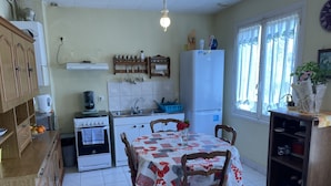 A kitchen with a dining table, chairs, a refrigerator, a stove, and a sink. - lovely quiet house (Lanester)