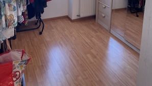 A room with wooden flooring, a clothing rack with various garments, a radiator, a chandelier, and a large mirror reflecting the room. - lovely quiet house (Lanester)