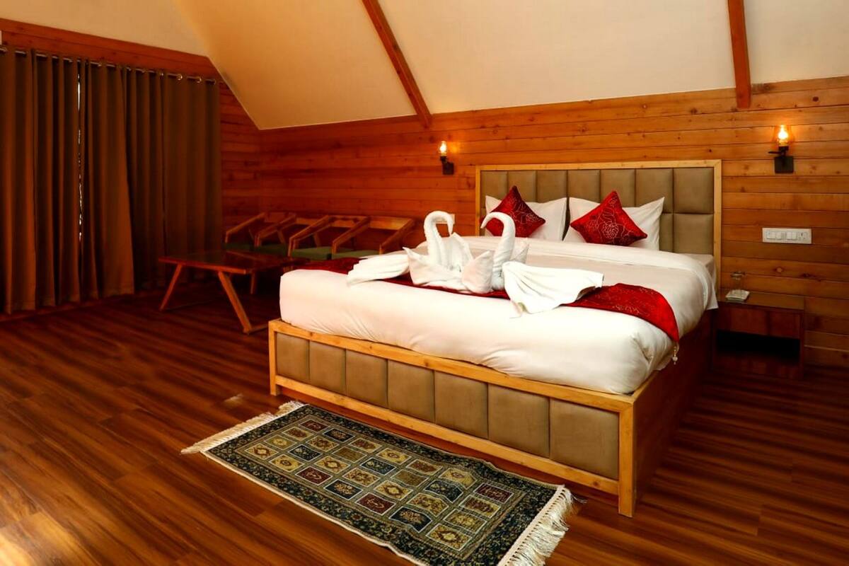 Een slaapkamer met houten lambrisering, een bed, kussens en een decoratief vloerkleed.