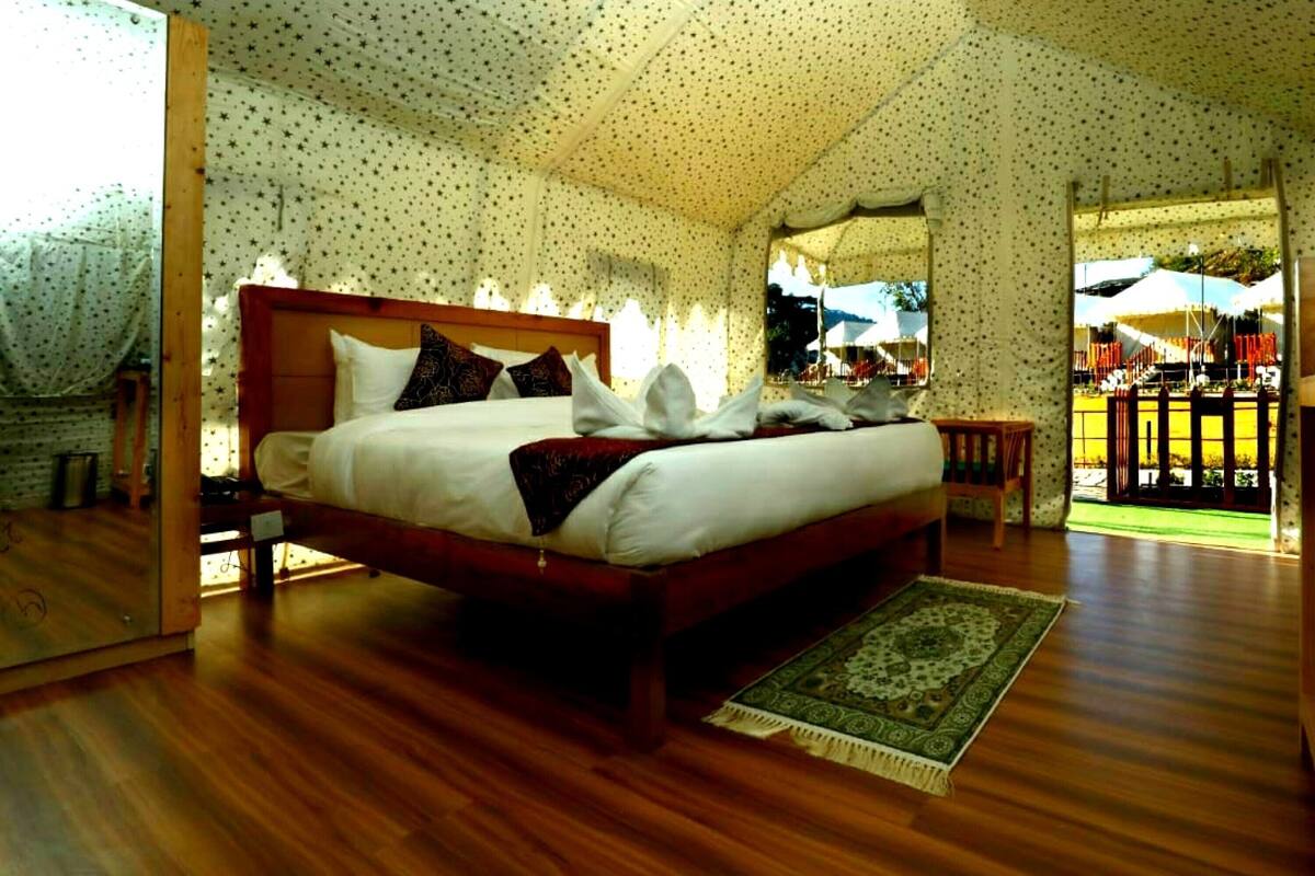 Een ruime slaapkamer met een groot bed, houten hoofdbord en uitzicht buiten door een groot raam.