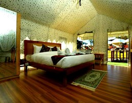 Un dormitorio espacioso con una cama grande, cabecera de madera y vistas al exterior a través de un ventanal amplio.