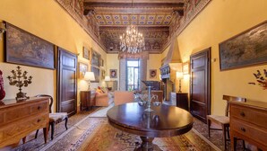 A grand room with a large wooden table, ornate ceiling, and classic furniture.