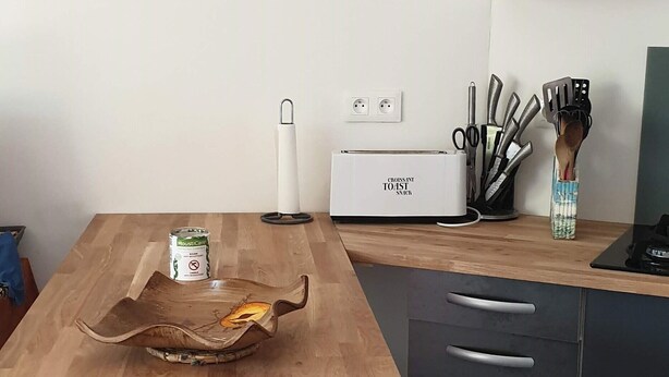 A kitchen with a wooden table, two stools, a toaster, and a knife block. - BEAUTIFUL BRAND-NEW STUDIO APARTMENT (Le teich)
