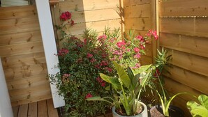 A wooden fence with a potted plant and flowers in the foreground. - BEAUTIFUL BRAND-NEW STUDIO APARTMENT (Le teich)