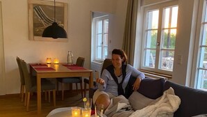 Een woonkamer met een bank, een eettafel en een ronde salontafel met kaarsen.