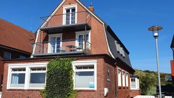 Ein zweistöckiges Backsteinhaus mit Balkon, kleinem Garten und einer Straßenlaterne.