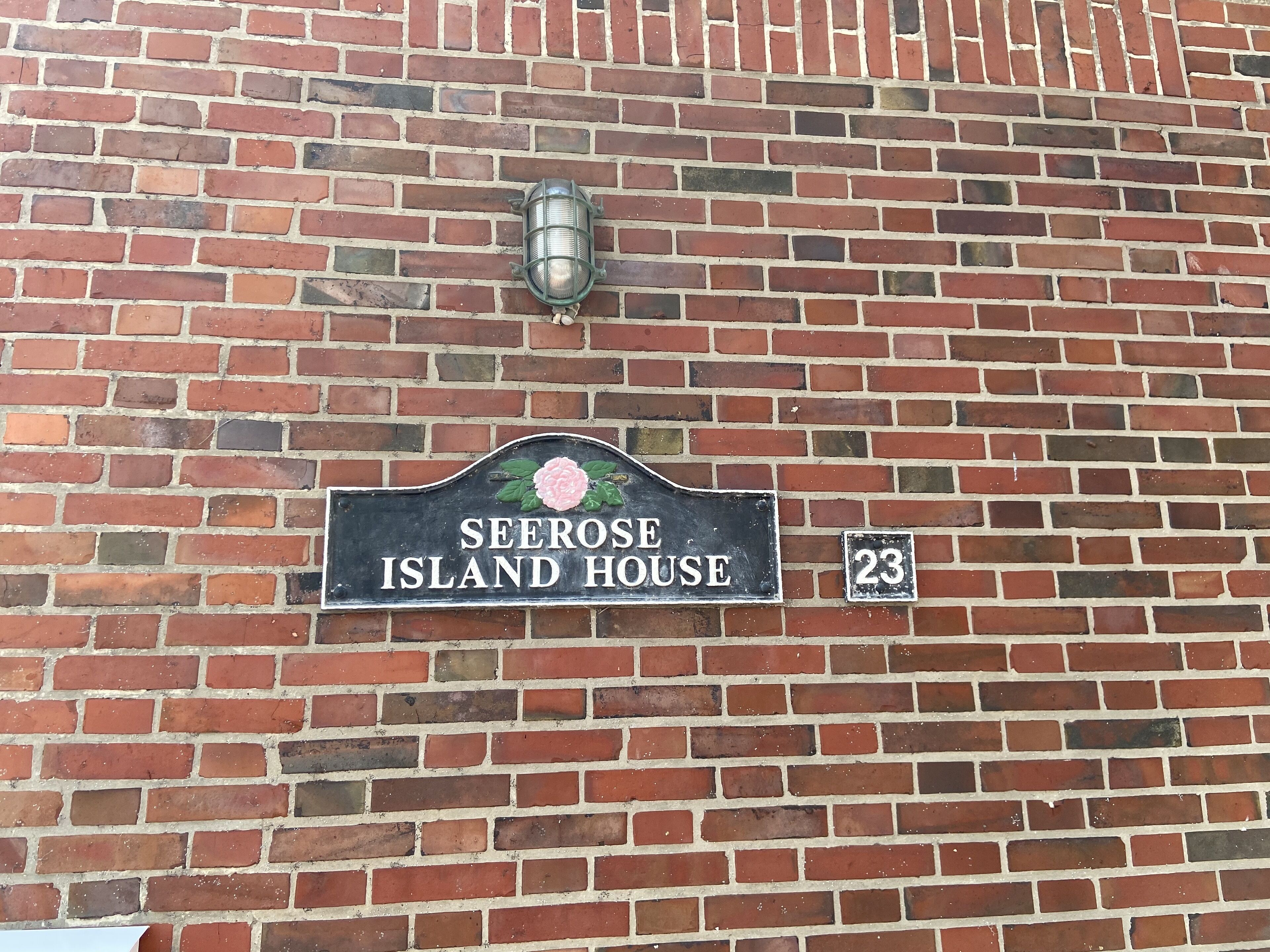 Un muro de ladrillo con un letrero que dice "SEEROSE ISLAND HOUSE" y el número "23".