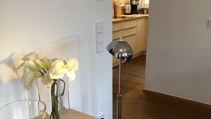 Een moderne keuken met houten kastjes, een koffieapparaat en een vaas met bloemen op het aanrecht.
