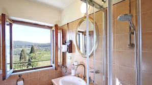 Une salle de bain avec une grande fenêtre, un lavabo, des toilettes et une douche.