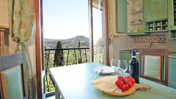 Un coin repas avec une table dressée pour deux personnes, une bouteille de vin et une vue sur la campagne.