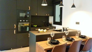 Una cuina moderna amb armaris foscos, una illa central i il·luminació penjant.