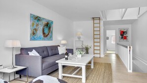 Un salon moderne avec un canapé gris, une table basse blanche et un tableau accroché au mur.