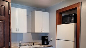 A compact kitchen with white cabinets, a white refrigerator, a stove, and a coffee maker. - Cute & cozy 1 bedroom apartment - sleeps 4 (Negaunee)