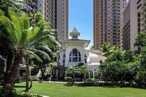 A hotel with a central building surrounded by palm trees and high-rise buildings.