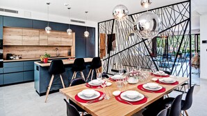 A modern dining area with a wooden table set for six, surrounded by black chairs. - Luxurious home in Marina with sauna (Marina)