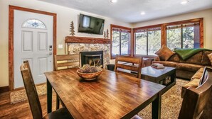 Una sala de estar acogedora con chimenea, muebles de madera y ventanas amplias que dan al exterior.