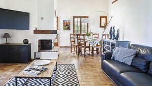 A living room with a fireplace, a dining area, and a black leather sofa. - Villa BELLE-VUE. Fully equipped (Taradeau)