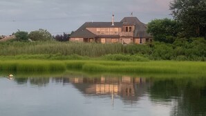 Een huis met een ruime voortuin en water ervoor.
