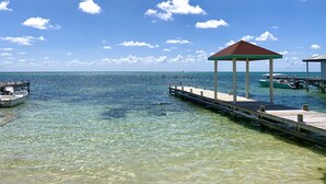A clear blue sky, a wooden dock extending into the water, and a small gazebo structure. - Quaint Studio at Belizean Reef Suites, Short Walk to Everything! (San Pedro - Town)