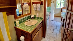 A bathroom with a sink, mirror, and wooden cabinets. - Quaint Studio at Belizean Reef Suites, Short Walk to Everything! (San Pedro - Town)