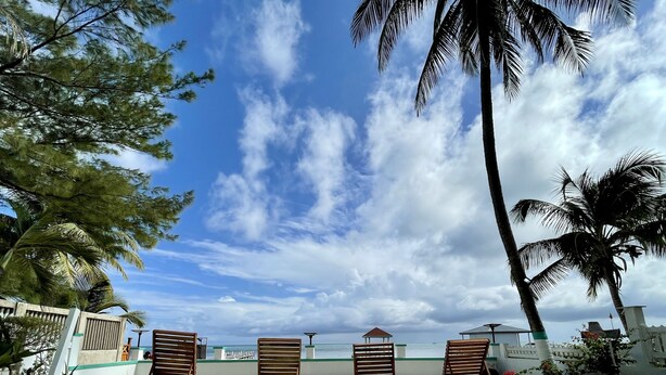 A beachside area with wooden lounge chairs and a view of the ocean. - Quaint Studio at Belizean Reef Suites, Short Walk to Everything! (San Pedro - Town)
