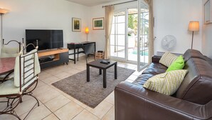 Un salon comprenant un téléviseur, un canapé, une table basse et un coin repas avec des chaises.