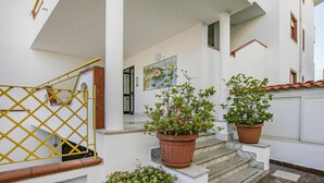 A white building with a staircase, yellow railing, and potted plants. - Stunning apartment in Ma Alba Adriatica (Ma Alba Adriatica)