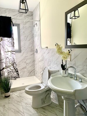 Un baño con inodoro, lavamanos y ducha.