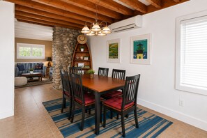 A dining area with a wooden table, six chairs, and a stone wall.