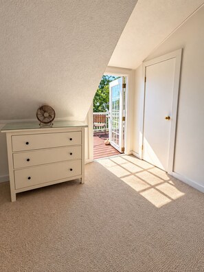 A room with a white dresser, a fan, and a door leading to an outdoor area.