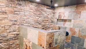 Un baño con pared de piedra y zona de lavamanos con azulejos.