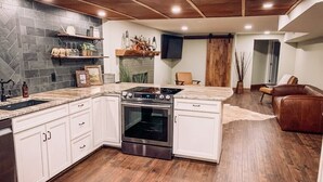Una cocina con armarios blancos, horno empotrado y salpicadero de piedra.