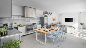 A modern kitchen with a central island, stainless steel appliances, and a dining area with light blue chairs. - Gorgeous home in Kastelir (Kastelir)