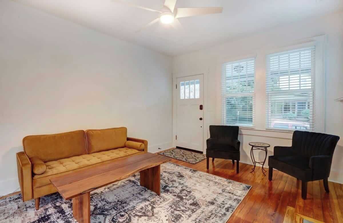 A living room with a sofa, two armchairs, a coffee table, and a ceiling fan.