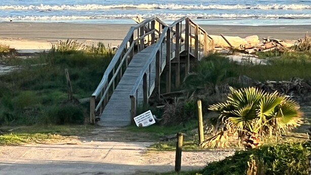 Un muelle de madera que conduce a una playa con vistas al océano.