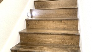 Una escalera de madera con barandilla a la izquierda, que conduce a un piso superior.