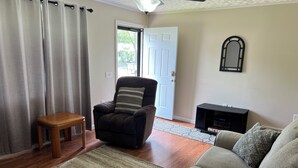 Ein Wohnzimmer mit einer Couch, einem Sessel, einem Holztisch und einem gemusterten Teppich.