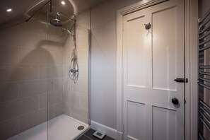 A modern bathroom with a glass shower enclosure, a white door, and a towel rack. - Contemporary Cottage in Ballater Village (Ballater)