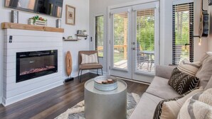 Una sala de estar moderna con chimenea, televisor y un área de descanso acogedora.