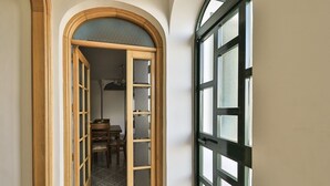 Ein Flur mit einer Holztür, die in einen Essbereich mit Tisch und Stühlen führt.