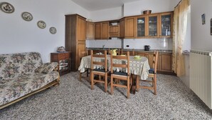 Eine kleine Küche mit Holzausstattung, einem Esstisch mit Stühlen und einem Sofa im Wohnbereich.