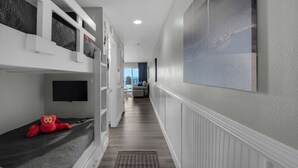A hallway with bunk beds, a television, and a large framed picture on the wall. - REMODELED! BeachFront, Bch Service, Pool, wifi, Kitchen, grill (Destin)