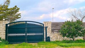 A gated entrance with a stone wall and a metal gate.