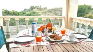 A balcony table set with breakfast items, including croissants, orange juice, and a bottle of milk.