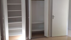 Una habitación con un armario blanco, una puerta cerrada y una lámpara colgante.