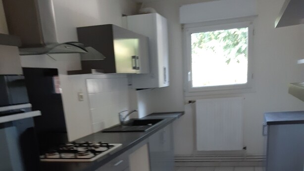 Cocina con armarios blancos, encimera negra y ventana con vistas a zonas verdes.