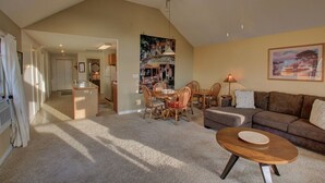 Een ruime woonkamer met een hoge plafond, een eettafel met stoelen, een bank en een salontafel.